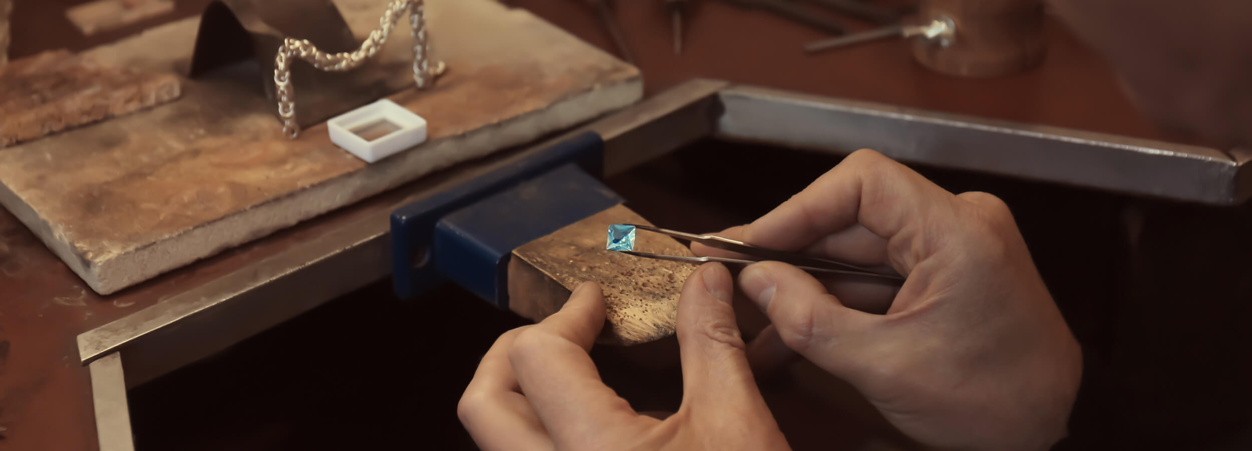 Jeweler holding blue gemstones in tweezers  