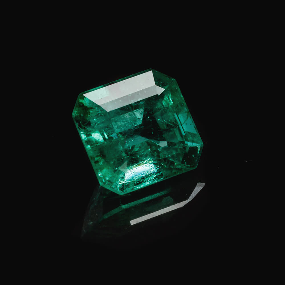Natural green emerald with inclusions on black background.